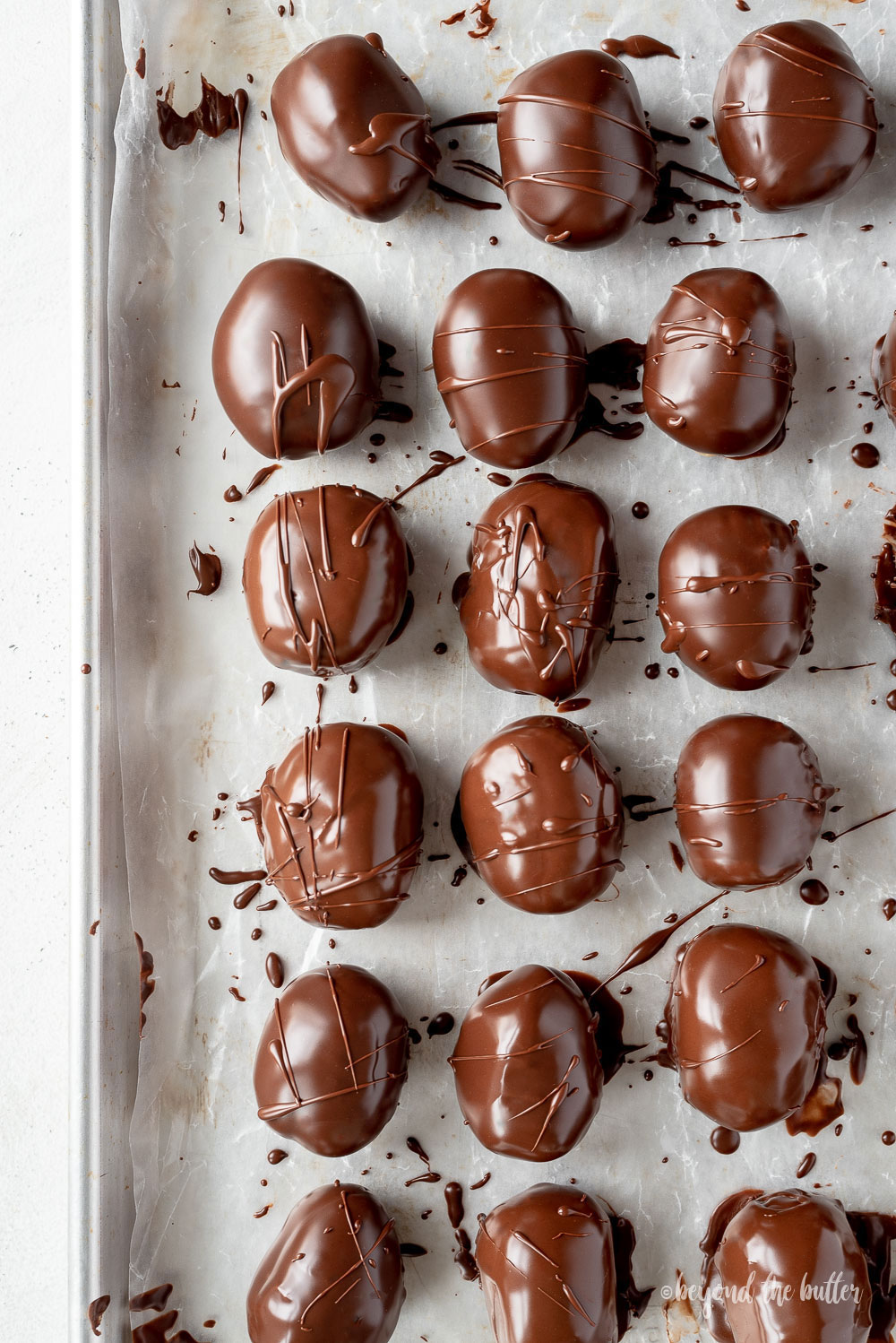 Overhead image of chocolate covered peanut butter eggs on a baking sheet | © Beyond the Butter, LLC