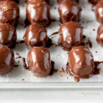 Angled image of just dipped chocolate covered peanut butter eggs on a baking sheet.