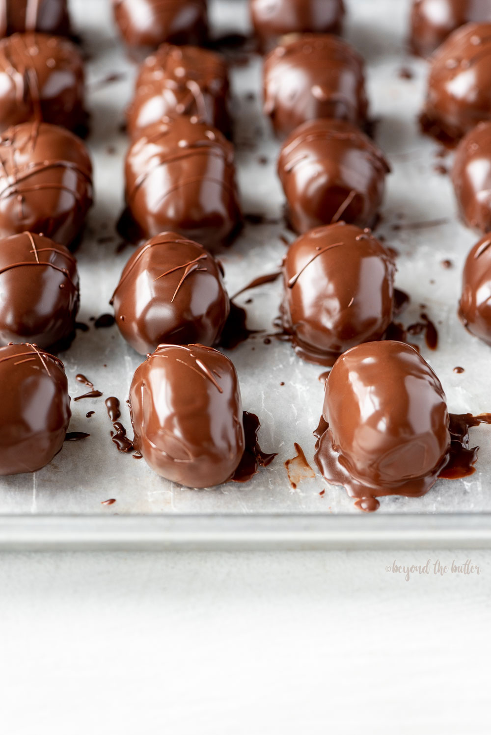 Angled photo chocolate covered peanut butter eggs on a baking sheet | Image and Copyright Policy: © Beyond the Butter, LLC