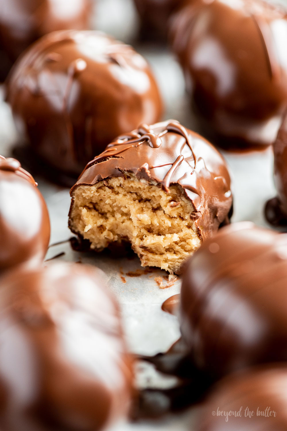 Close up photo of half eaten chocolate covered peanut butter egg | Image and Copyright Policy: © Beyond the Butter, LLC