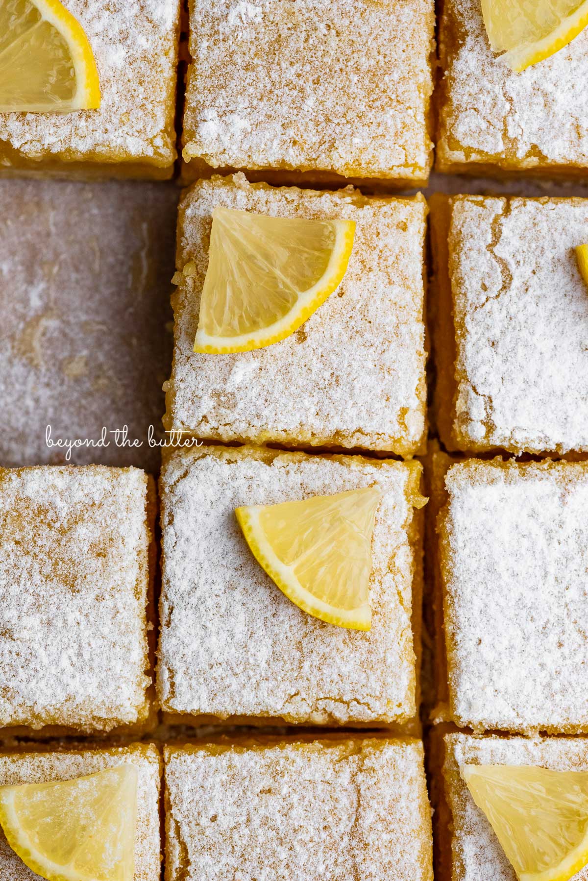 Tart and tangy lemon bars on parchment paper | © Beyond the Butter®