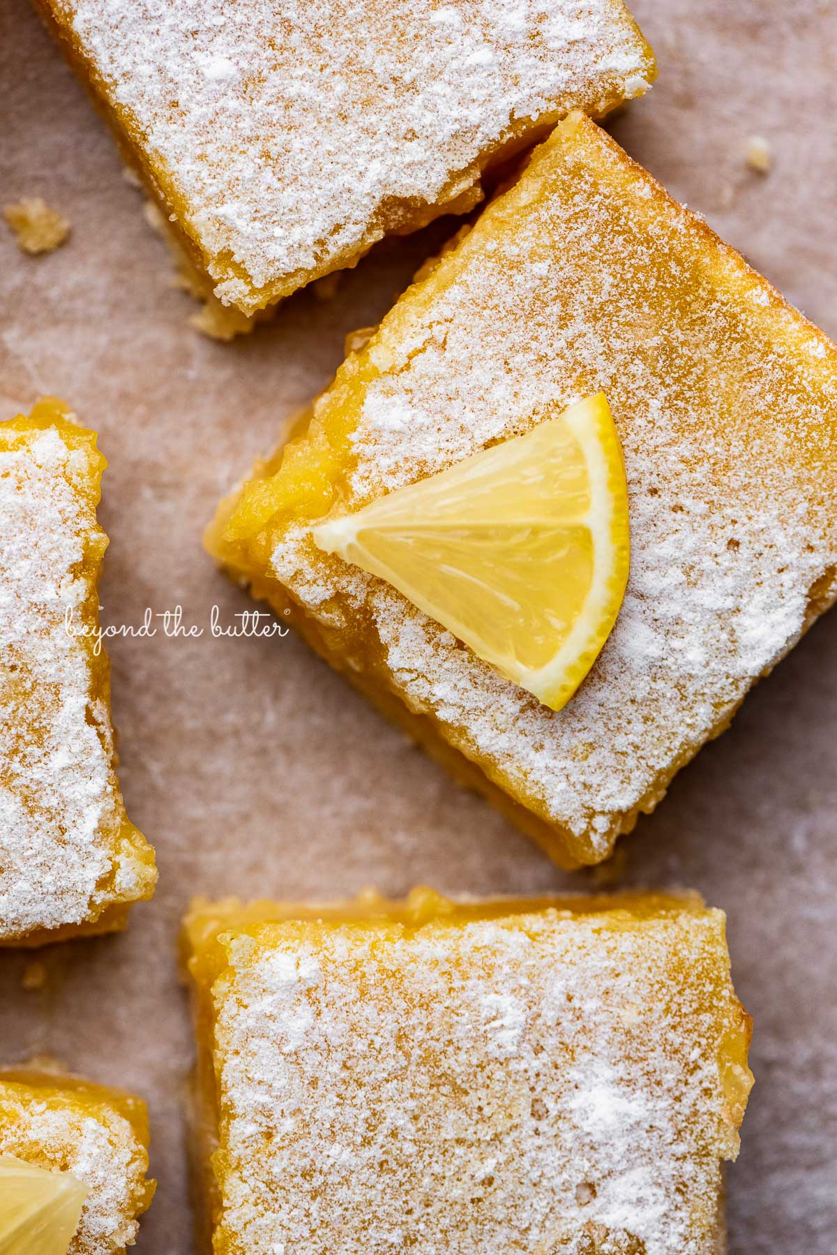 Tart and tangy lemon bars on parchment paper | © Beyond the Butter®