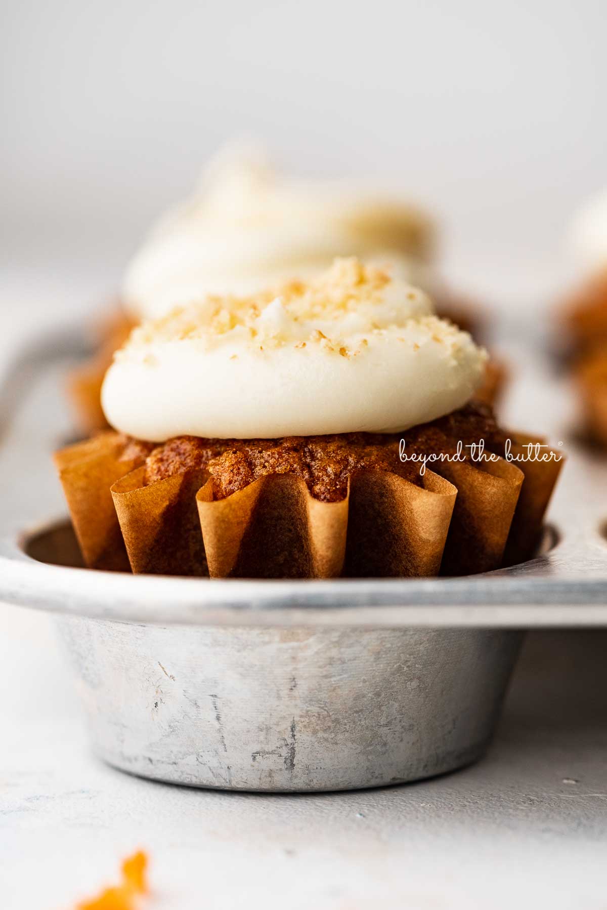 Closeup image of carrot cake cupcakes in a vintage cupcake tin | © Beyond the Butter®