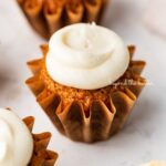 Super moist carrot cake cupcakes topped with cream cheese frosting on a white background.