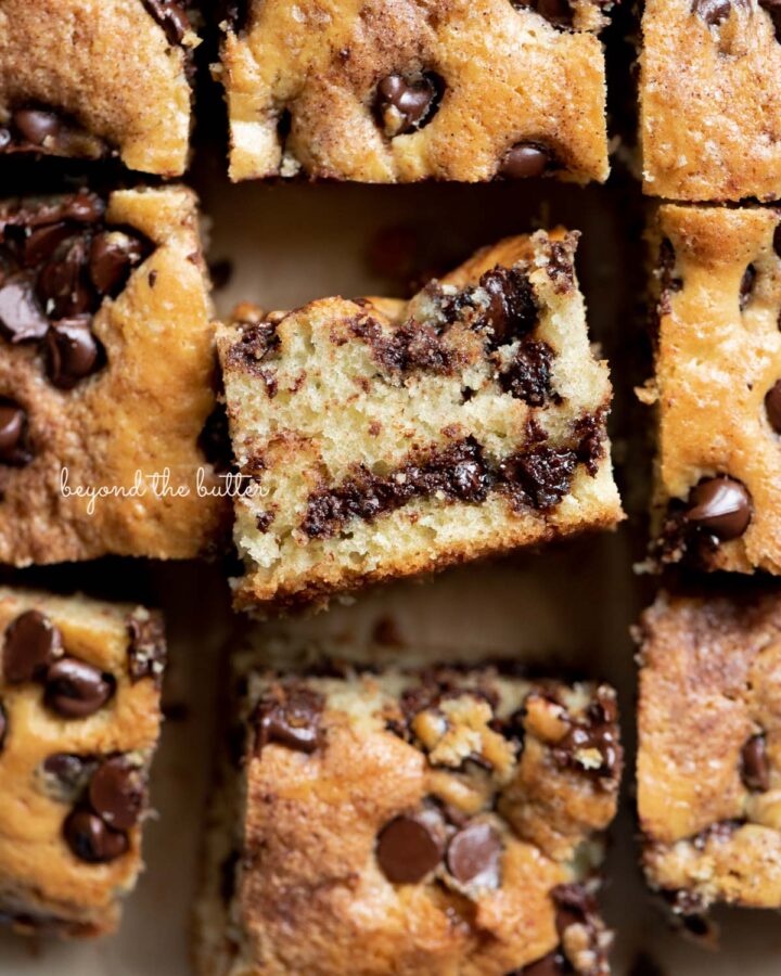 Slices of chocolate chip sour cream coffee cake on brown parchment paper with center slice on its side.