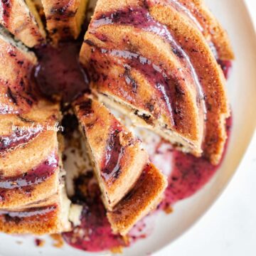 Overhead image of sliced blueberry bundt cake with blueberry glaze drizzled over the top | All Images © Beyond the Butter, LLC