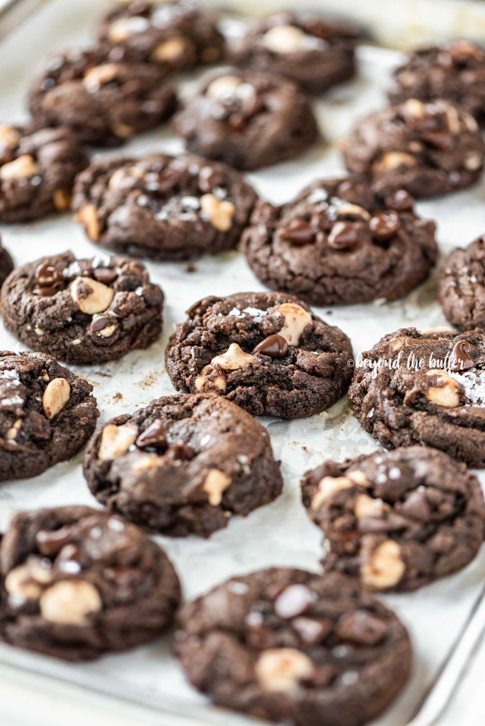 Angled image of just baked double chocolate salted caramel cookies on a baking sheet | All Images © Beyond the Butter™