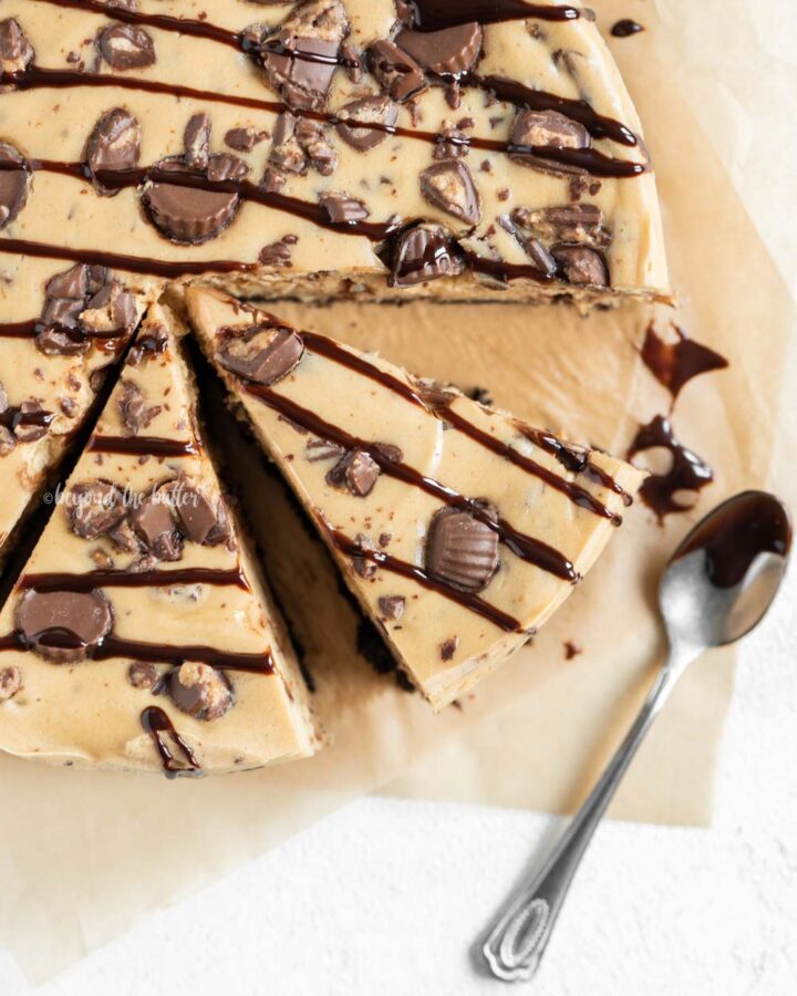 Close up overhead image of sliced Reese's Peanut Butter Cup Cheesecake drizzled with chocolate.