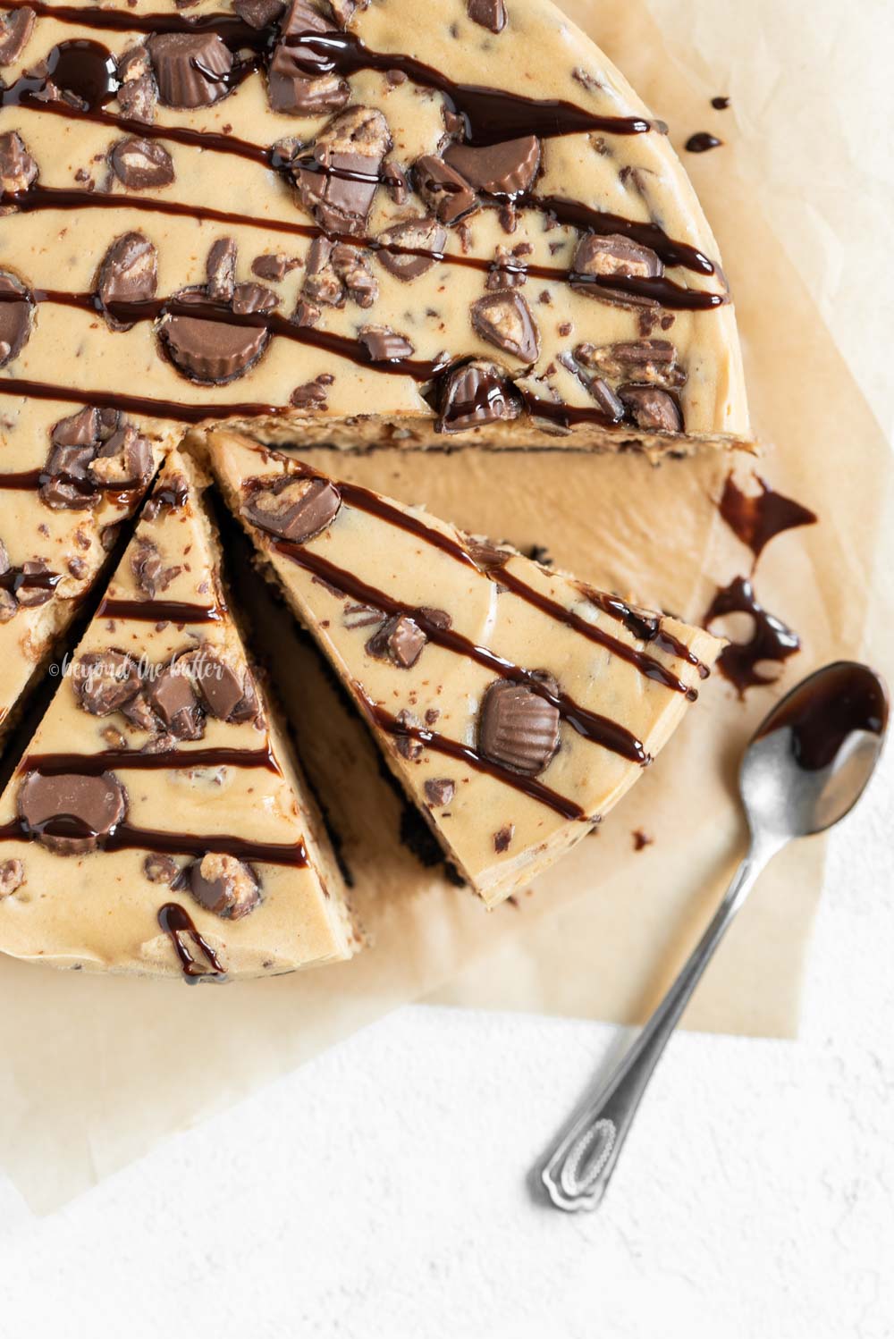 Close up overhead image of sliced Reese's Peanut Butter Cup Cheesecake drizzled with chocolate.