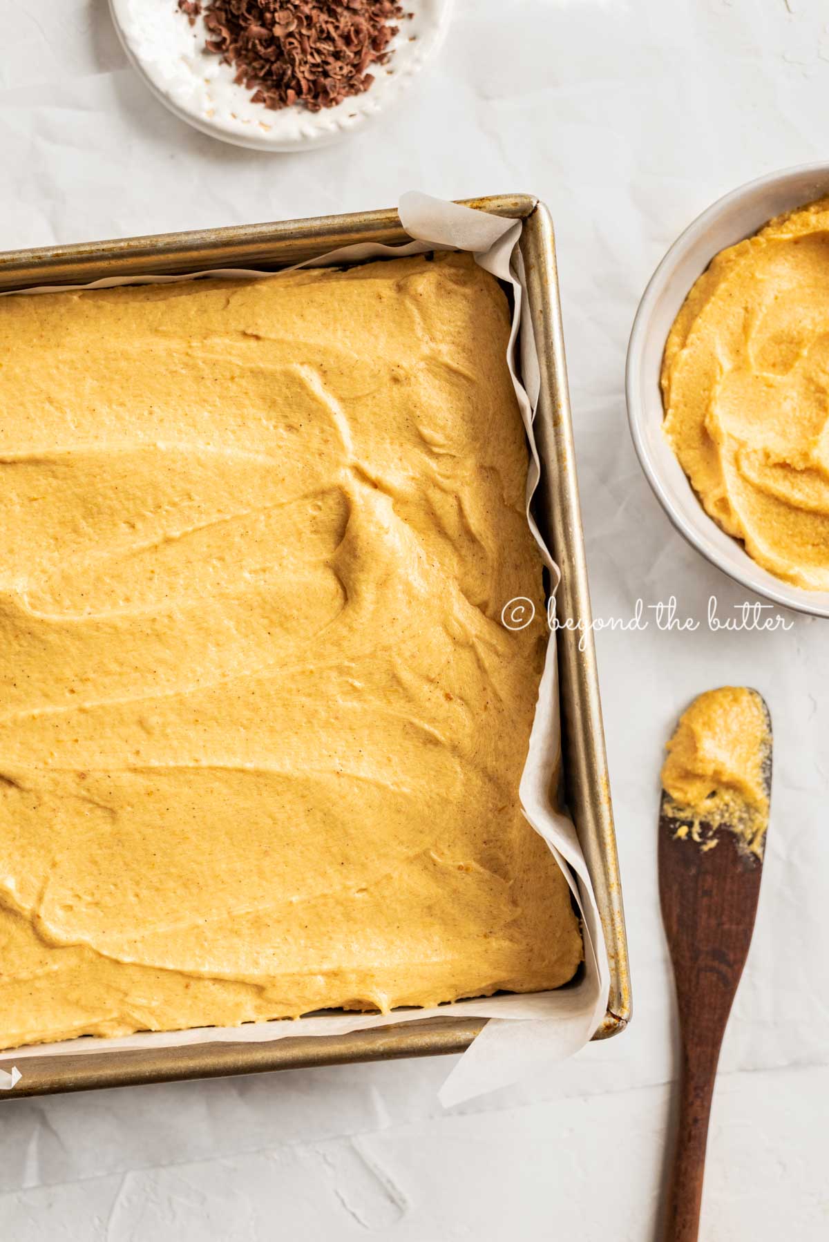baking pan with fudgy chocolate brownies just frosted with pumpkin buttercream frosting | All Images © Beyond the Butter™