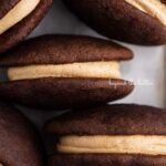 Chocolate peanut butter whoopie pies on a parchment lined baking pan.