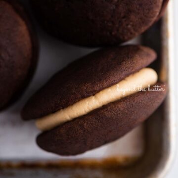 Closeup overhead image of chocolate peanut butter whoopie pies on a parchment lined baking pan | © Beyond the Butter®