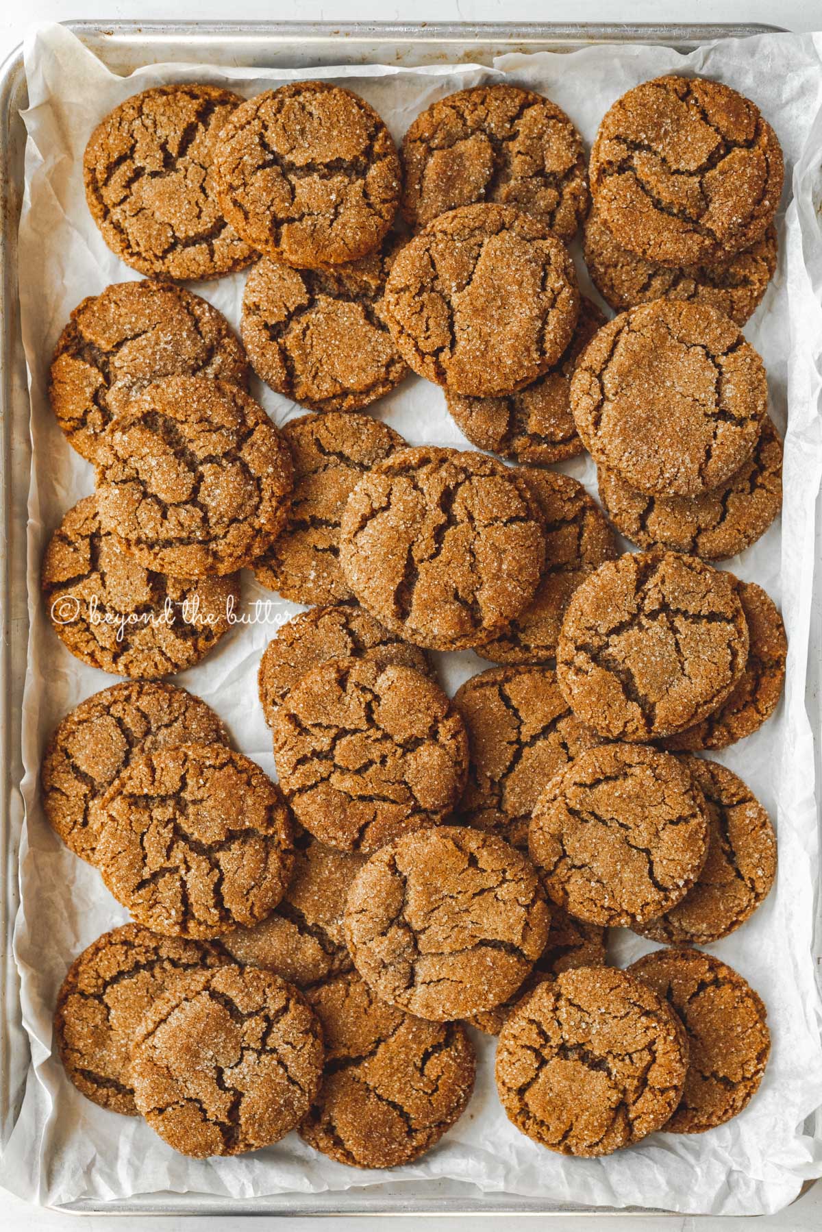 Parchment lined baking sheet topped with super soft molasses cookies | All Images © Beyond the Butter™
