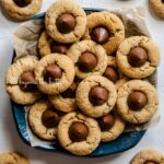 Overhead image of classic peanut butter blossoms on a parchment lined blue dessert platter.