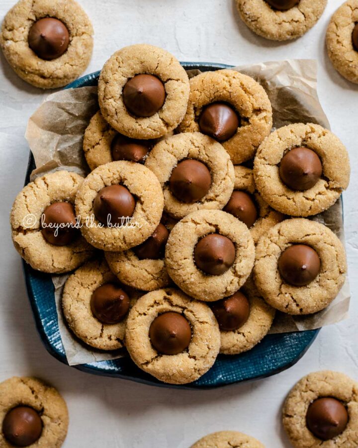 Overhead image of classic peanut butter blossoms on a parchment lined blue dessert platter.