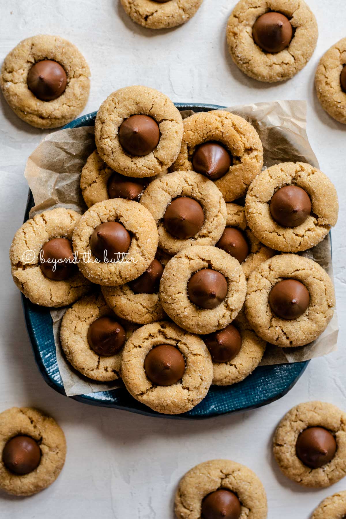 Overhead image of classic peanut butter blossoms on a parchment lined blue dessert platter | All Images © Beyond the Butter™