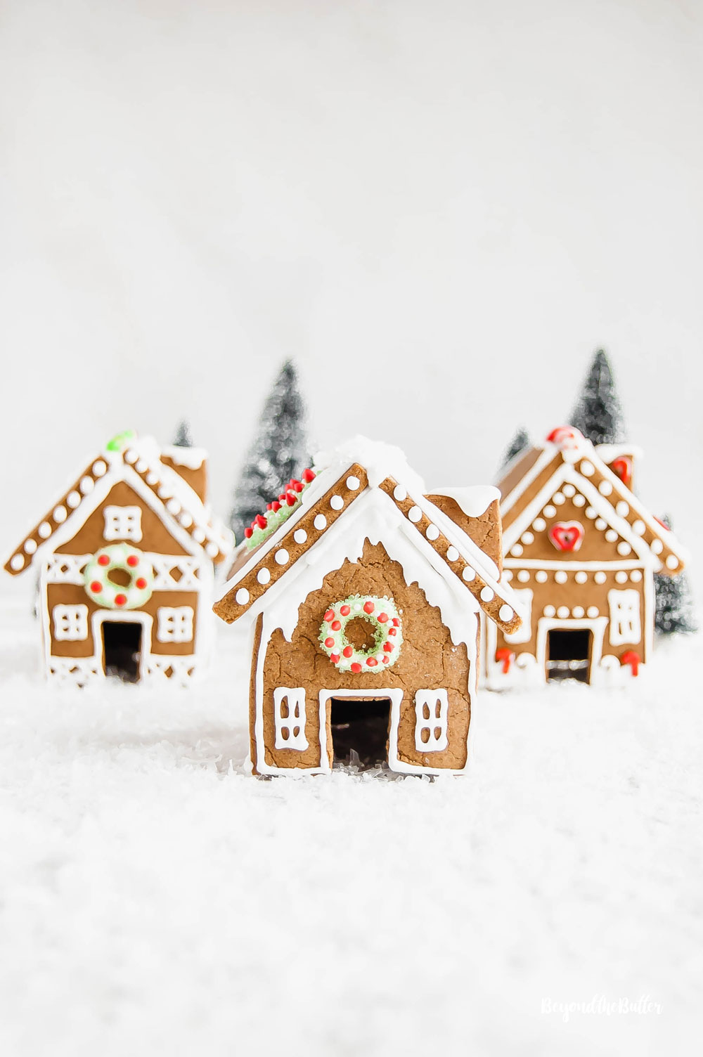 Homemade Gingerbread Houses - 3 gingerbread houses with trees in the background | All Images © Beyond the Butter, LLC