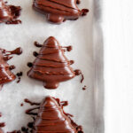 Chocolate covered peanut butter trees on parchment paper lined baking sheet.