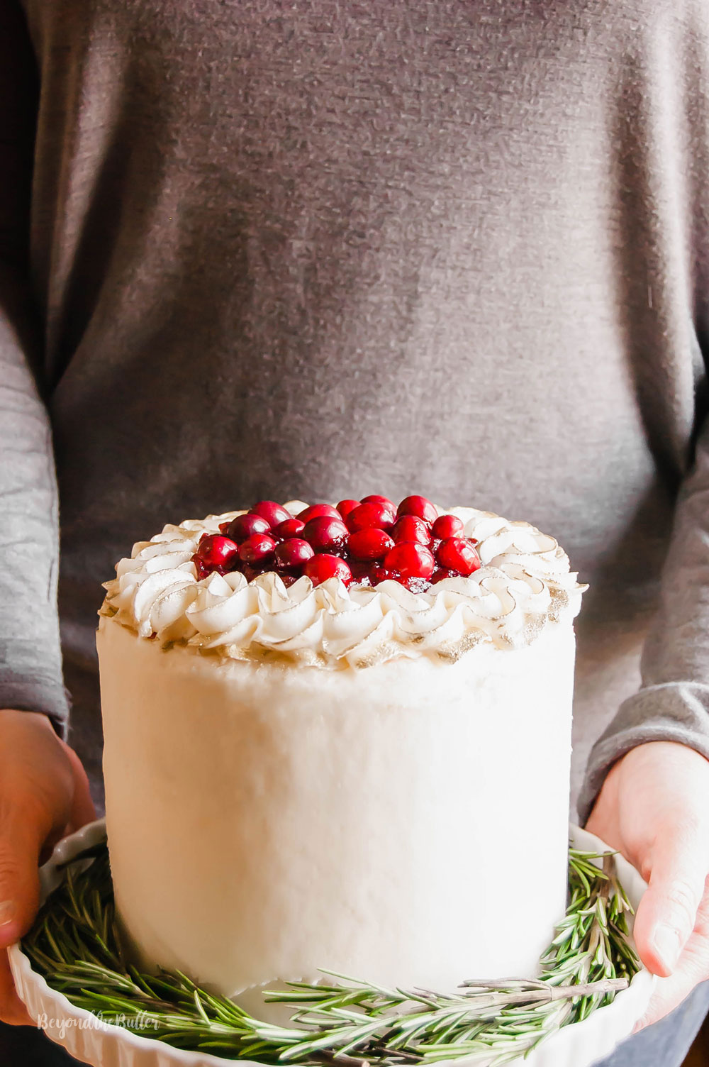 Gingerbread Cake | Person holding Gingerbread Cake with Maple Buttercream Frosting and Cranberry  Compote on a cake stand | Image Credit: Beyond the Butter, LLC
