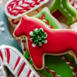 Closeup of holiday themed cut out sugar cookies on a red and white dessert plate.