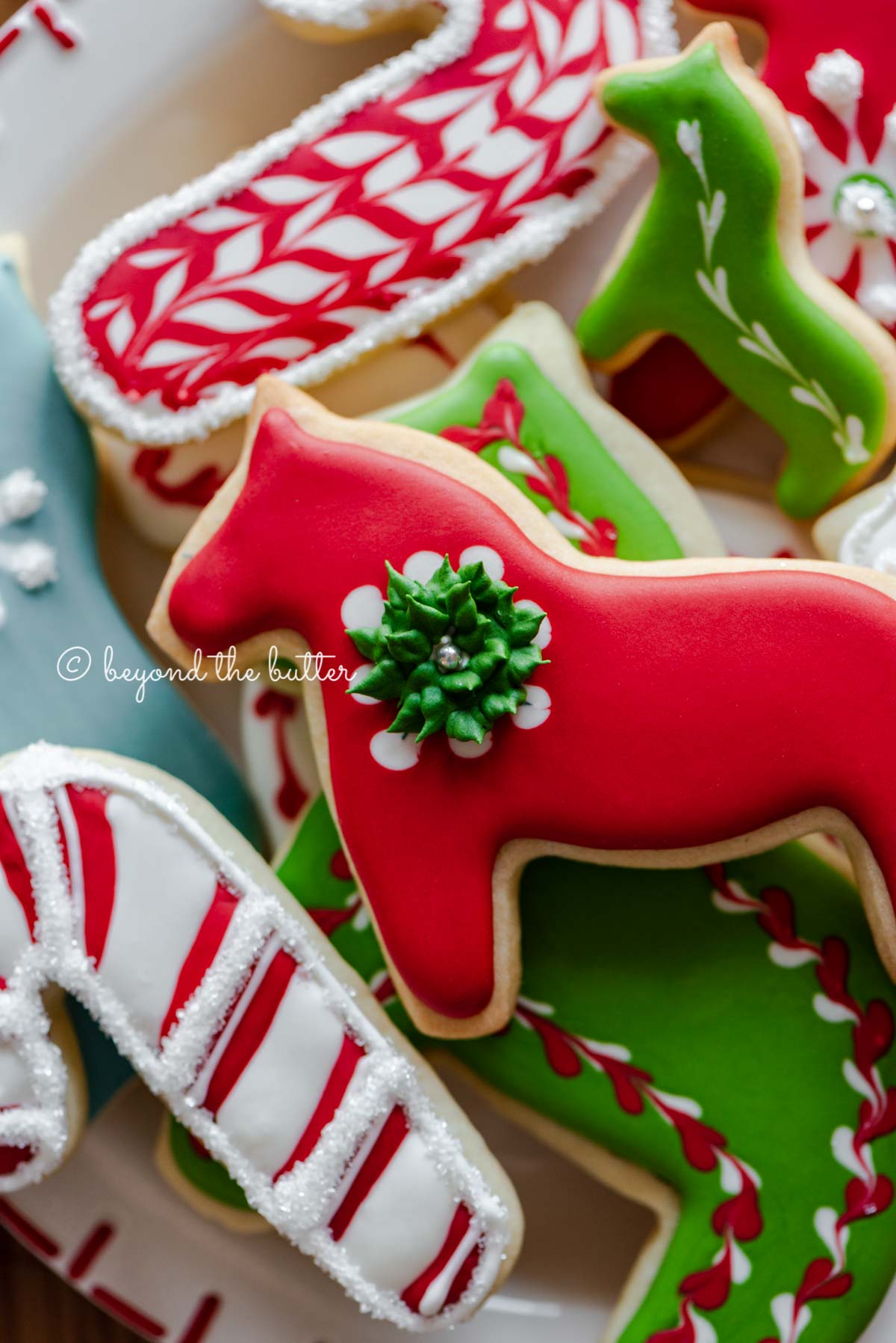 Closeup of holiday themed cut out sugar cookies on a red and white dessert plate.