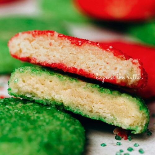 Randomly placed almond sprinkle cookies with the center cookies stacked and split in half to see the soft centers.