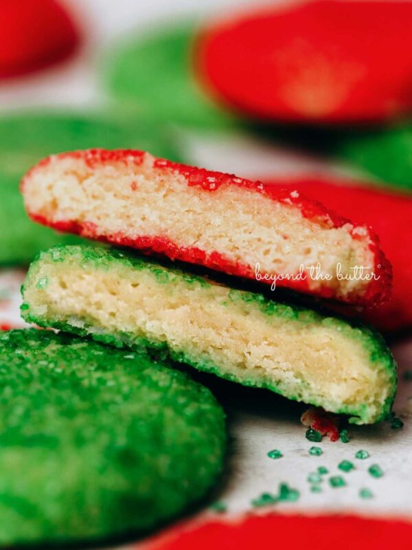 Randomly placed almond sprinkle cookies with the center cookies stacked and split in half to see the soft centers.