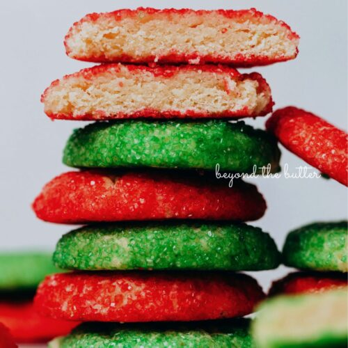 Stack of red and green sugared almond sprinkle cookies on a white background.