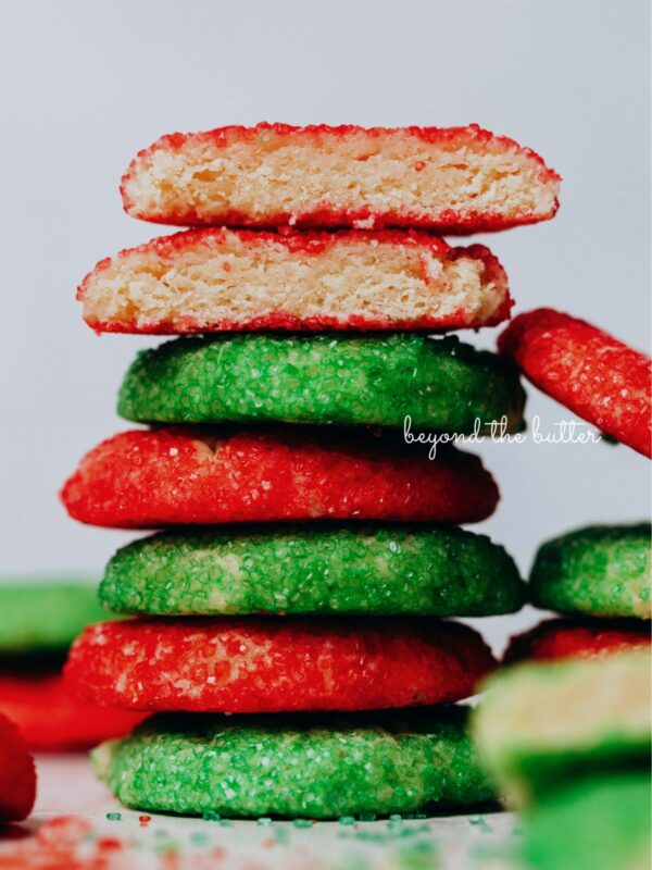 Stack of red and green sugared almond sprinkle cookies on a white background.