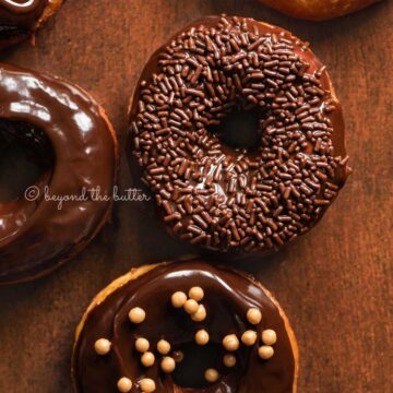 Chocolate glazed decorated donuts on dark wood background | All Images © Beyond the Butter™