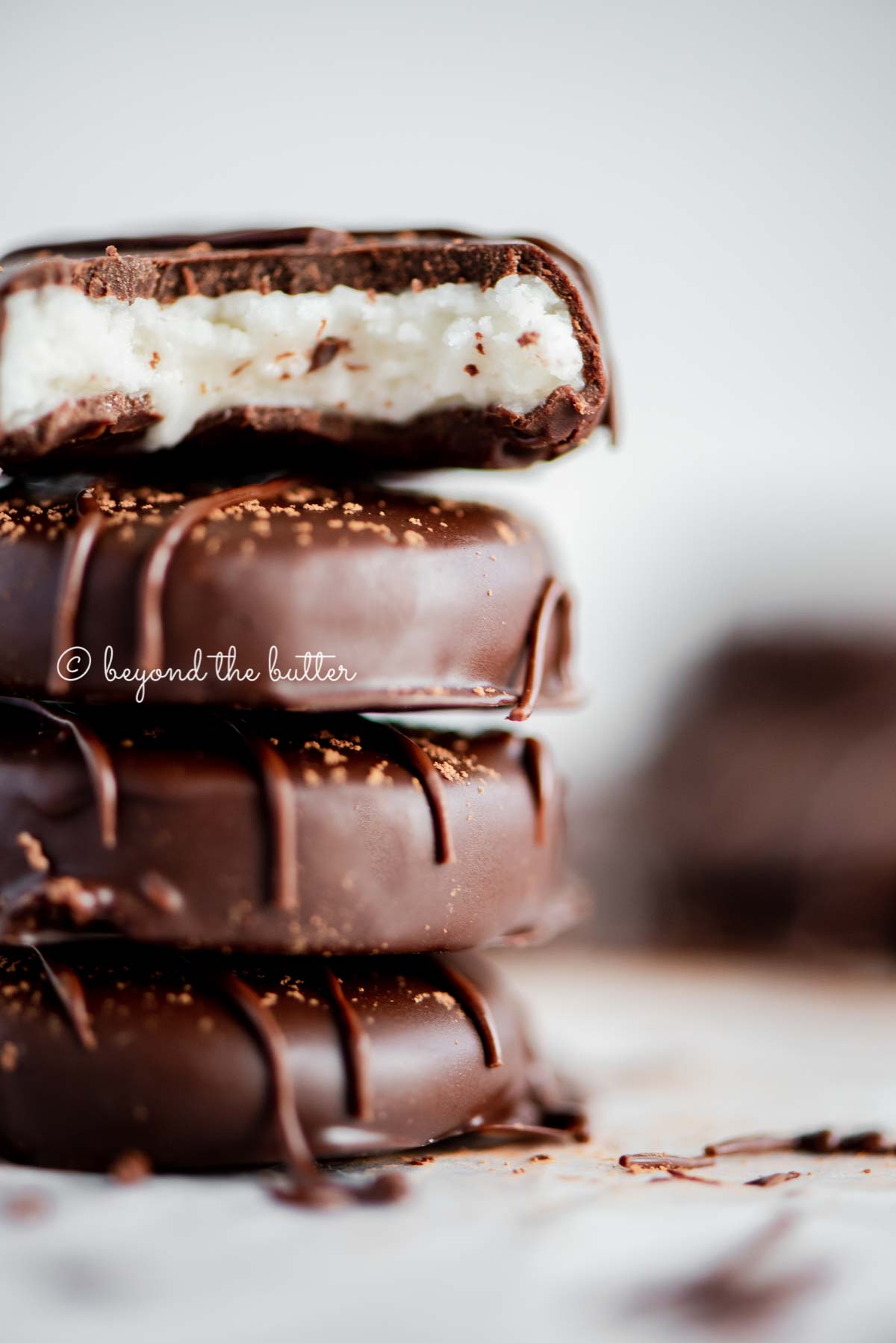 Stacked homemade peppermint patties with a bite taken out of the top patty | All Images © Beyond the Butter®