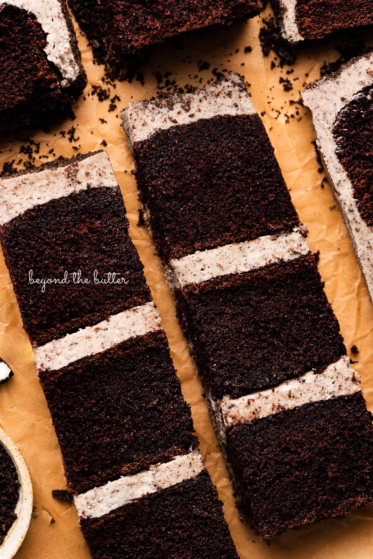 Slices of chocolate cake with oreo buttercream frosting on natural parchment paper from BeyondtheButter.com | © Beyond the Butter®