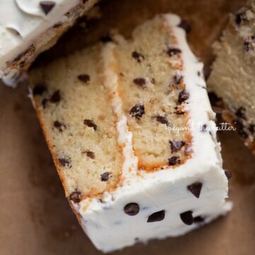Slice of 2 layer chocolate chip cake on it's side on a brown paper background | © Beyond the Butter®