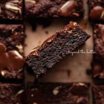 Double chocolate mint brownies on brown parchment paper background with the center brownie on its side | © Beyond the Butter®