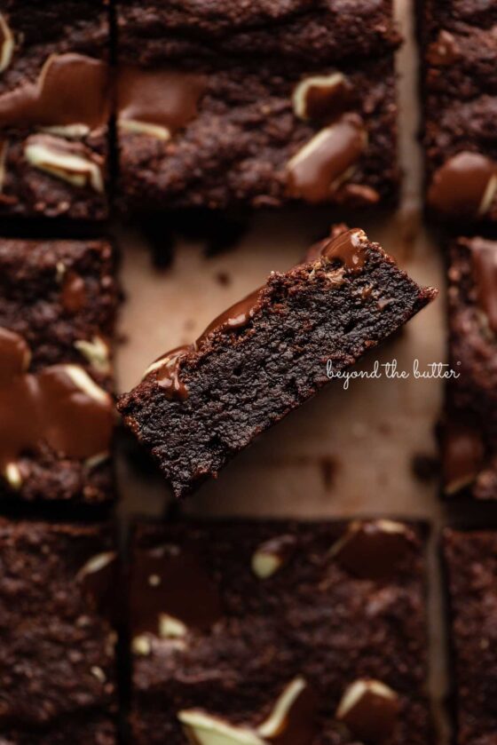 Double chocolate mint brownies on brown parchment paper background with the center brownie on its side.