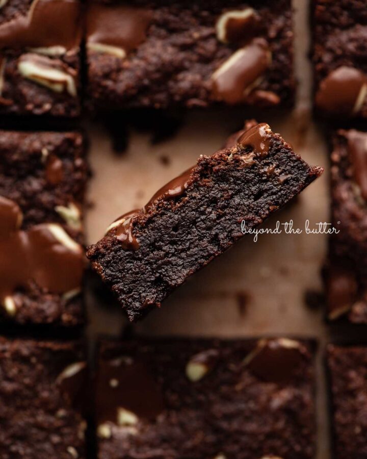 Double chocolate mint brownies on brown parchment paper background with the center brownie on its side.