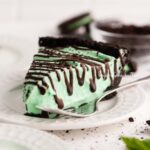 Dessert plates with slices of no bake mint chocolate pie with chocolate syrup drizzled over the top.