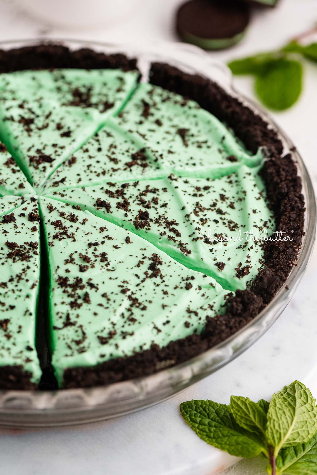 No bake mint chocolate pie sliced in a glass pie plate on a white background | © Beyond the Butter®