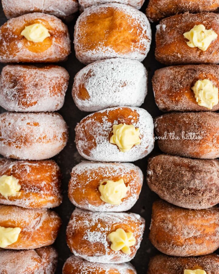 Rows of pennsylvania dutch fasnacht doughnuts filled with pastry cream.