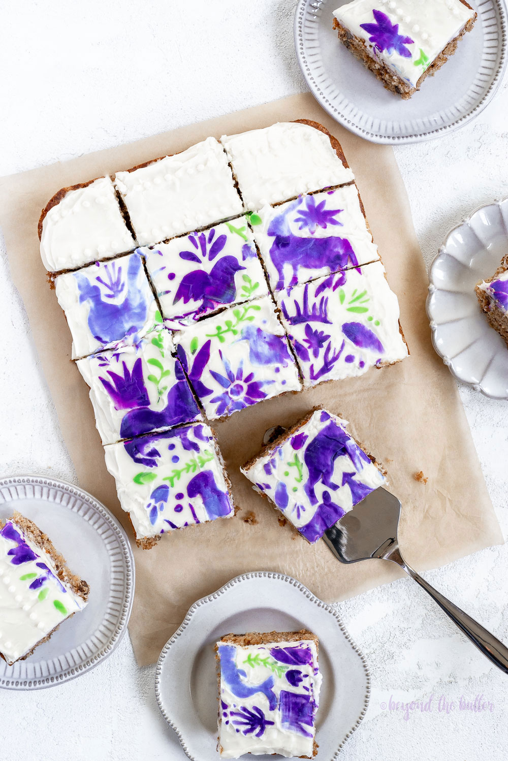 Hummingbird Sheet Cake with White Chocolate Cream Cheese Frosting | Overhead photo of Hummingbird Sheet Cake that's topped with a white chocolate frosting, and stenciled using purple and green frosting | Image and Copyright Policy: © Beyond the Butter, LLC.