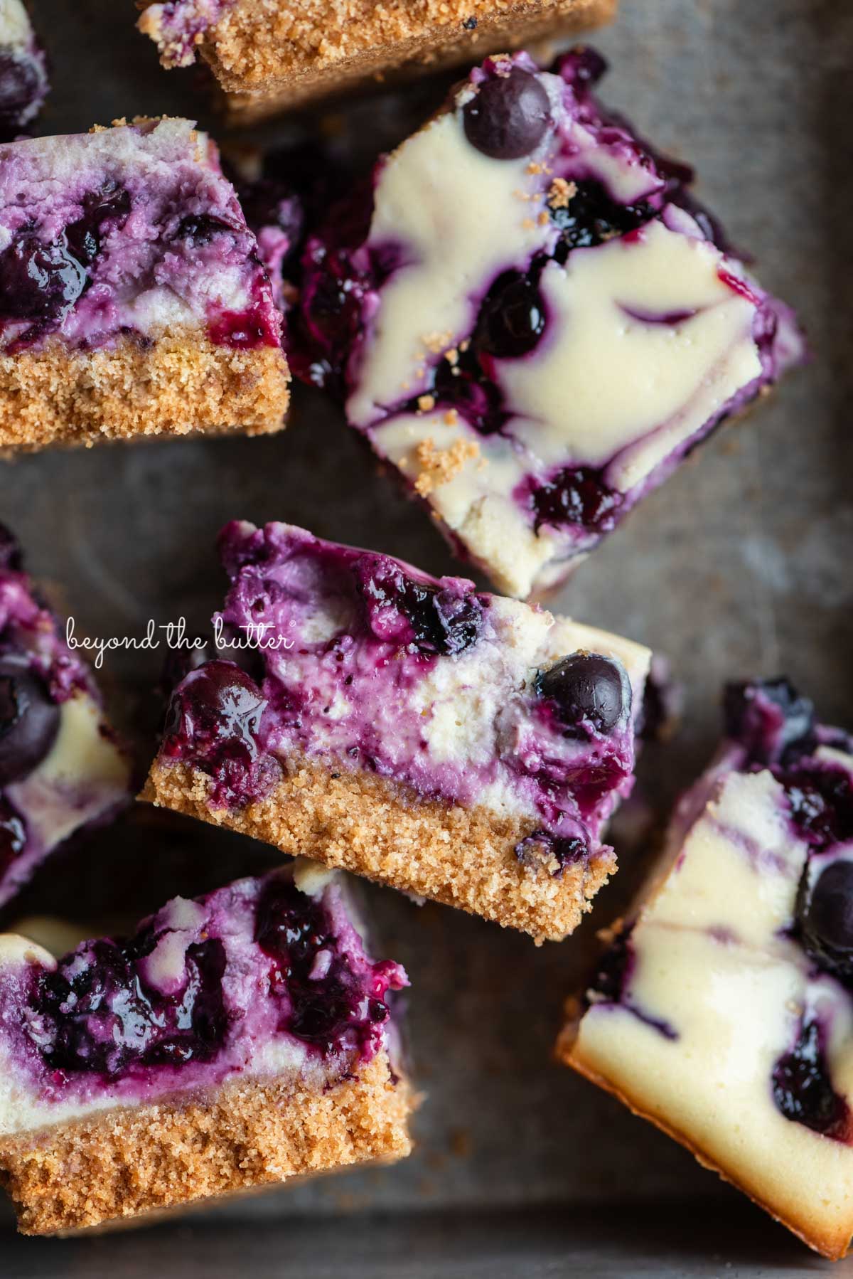 Sliced blueberry swirl cheesecake bars in a vintage baking pan from BeyondtheButter.com | © Beyond the Butter®