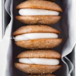 Row of apple cider whoopie pies packed in a parchment paper lined loaf pan.