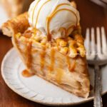Slice of easy homemade apple pie drizzled with caramel and topped with a scoop of vanilla bean ice cream.