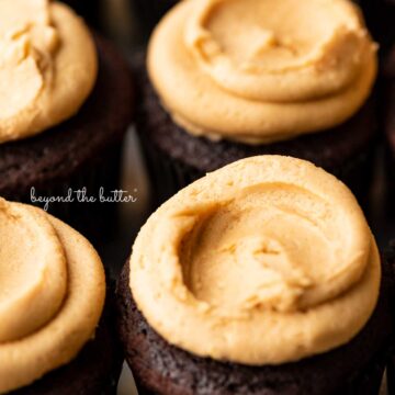 Close up image of devil's food cupcakes topped with peanut butter frosting on a baking sheet | © Beyond the Butter®