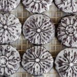 Overhead image of homemade glazed oreo snowflake cookies on a wire cooling rack.
