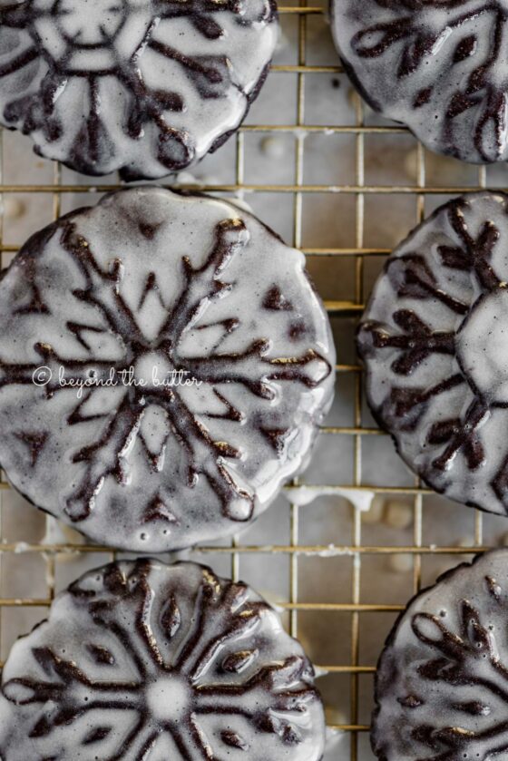 Overhead closeup image of homemade oreo snowflake cookies on a wire cooling rack | All Images © Beyond the Butter®