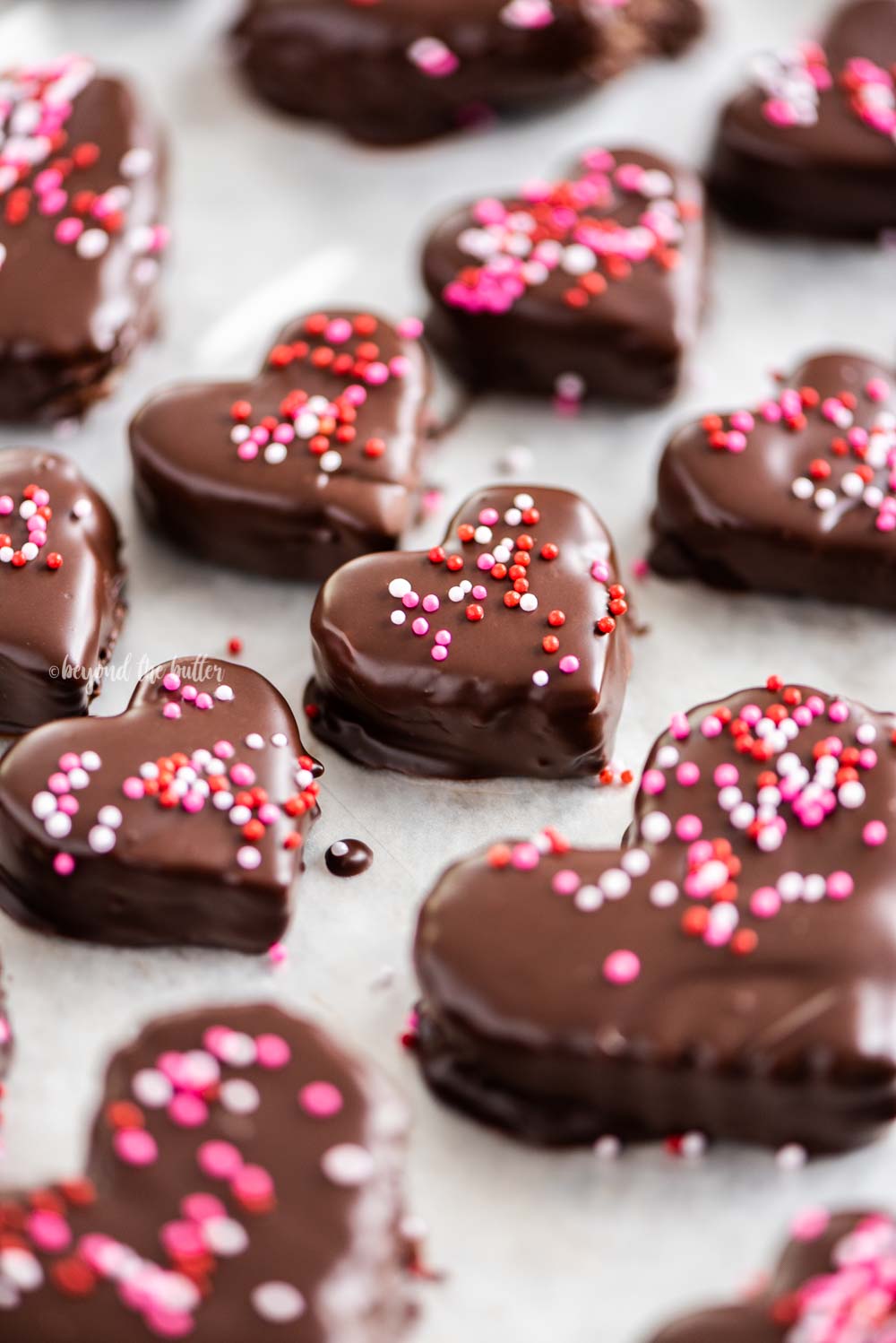 Overhead image of chocolate covered cookie dough hearts with sprinkles | All Images © Beyond the Butter, LLC