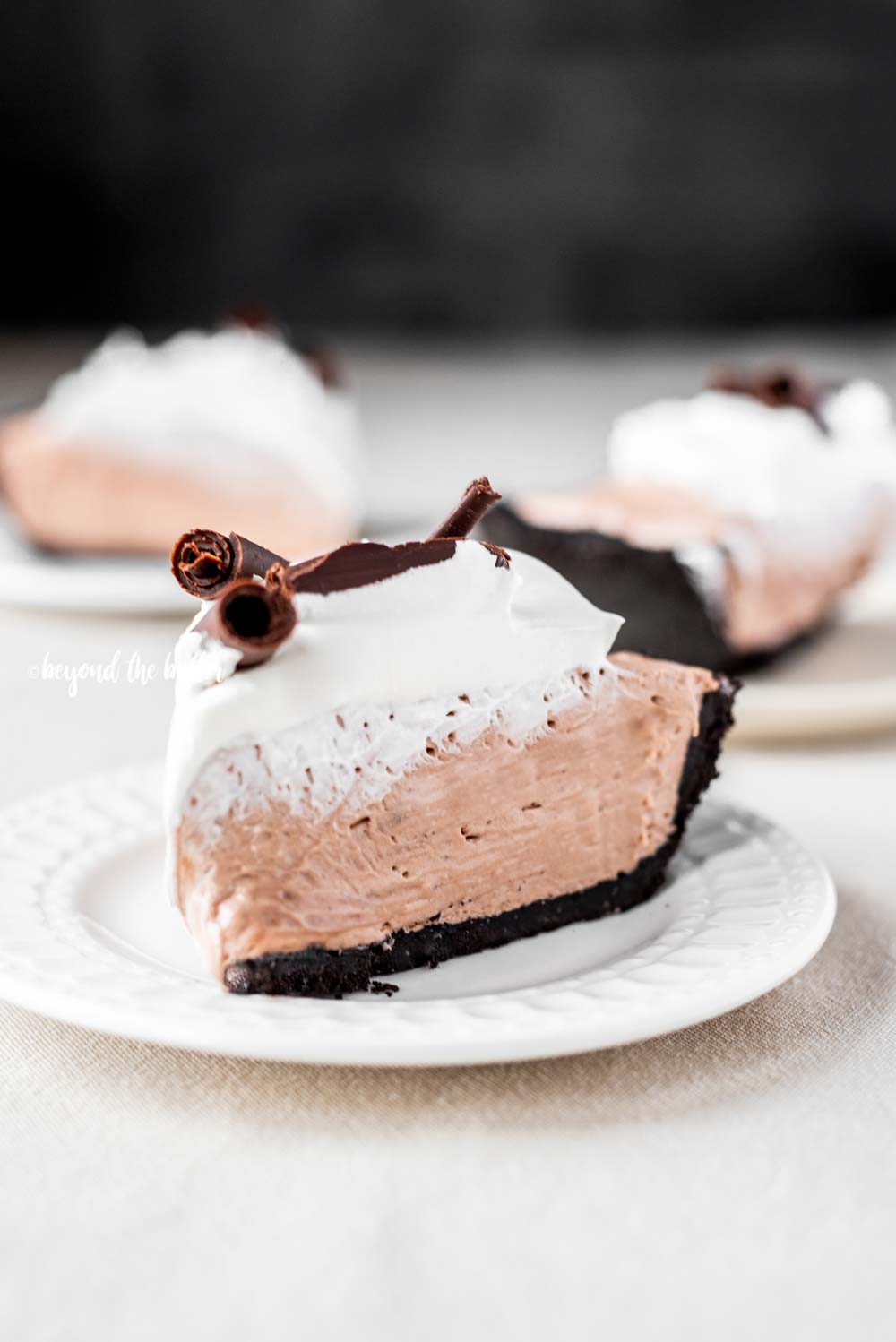 Slice of no-bake chocolate cream pie with chocolate wafer crust on dessert plates | All Images © Beyond the Butter™