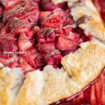 Angled close up image of a Berry Nutella Galette on a baking sheet with Nutella drizzled over the top.