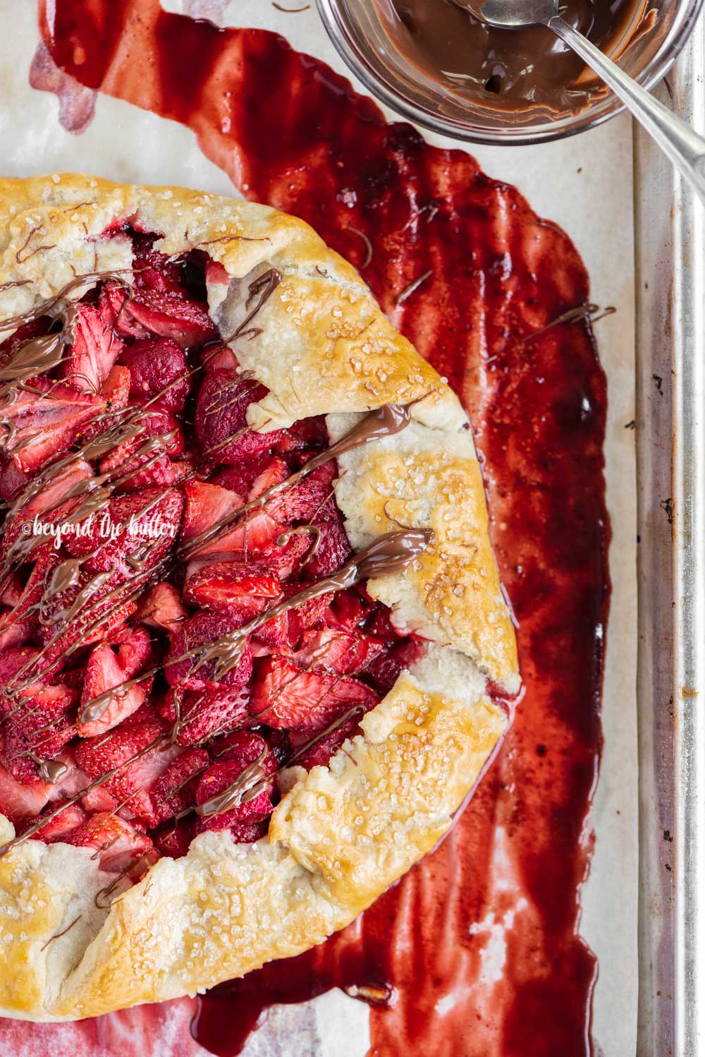 Overhead image of a Berry Nutella Galette on a baking sheet with Nutella drizzled over the top.